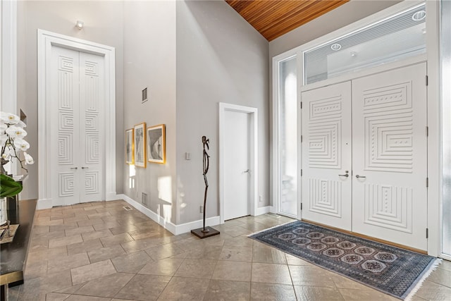 foyer entrance featuring high vaulted ceiling, visible vents, and baseboards