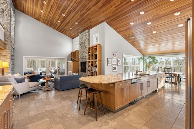 kitchen featuring wood ceiling, light stone counters, open floor plan, high vaulted ceiling, and a sink