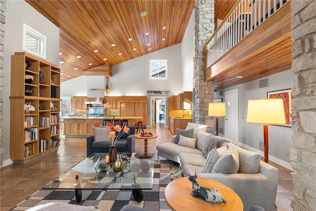 living area with decorative columns, wood ceiling, a high ceiling, and visible vents