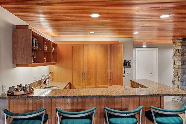 kitchen featuring dark stone counters, wood ceiling, a sink, and a peninsula