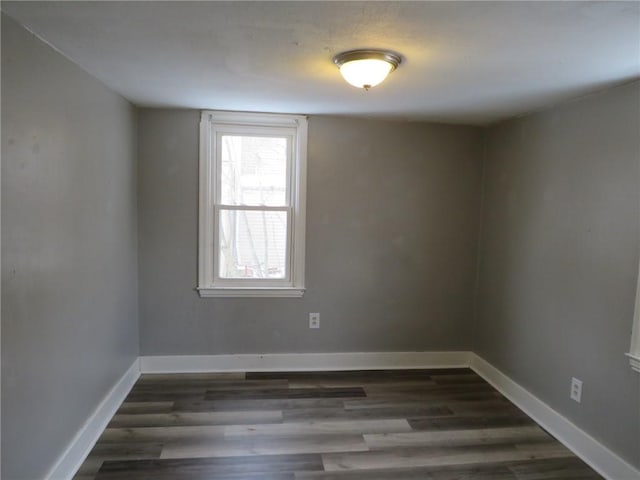 spare room featuring dark wood-style floors and baseboards