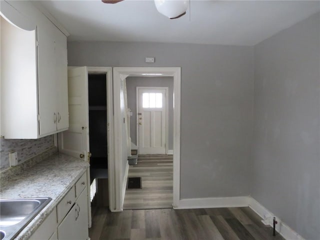 kitchen with dark wood-style floors, tasteful backsplash, light countertops, white cabinets, and baseboards