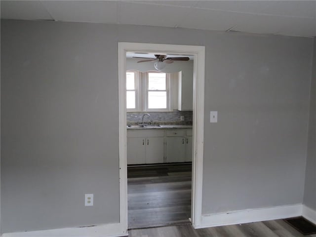 interior space featuring dark wood-style floors, ceiling fan, baseboards, and a sink