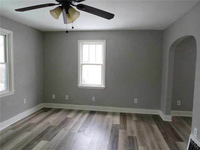 empty room with ceiling fan, plenty of natural light, and wood-type flooring