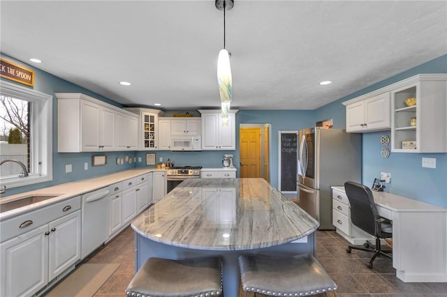 kitchen with sink, white cabinetry, hanging light fixtures, appliances with stainless steel finishes, and a kitchen island