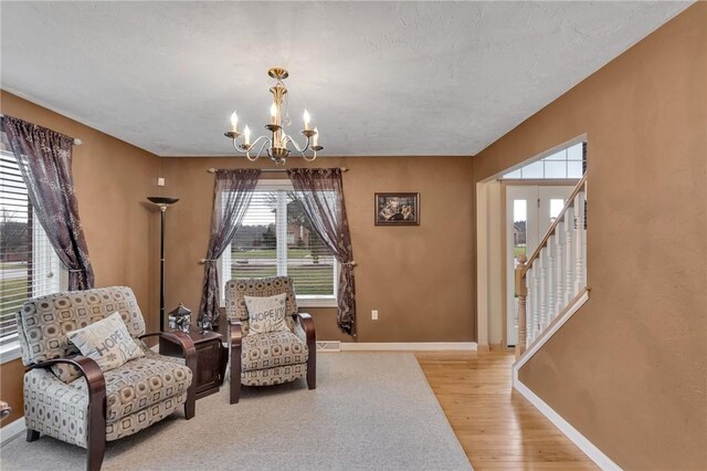 sitting room with light wood-type flooring and an inviting chandelier