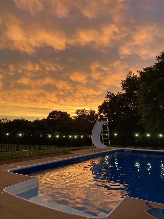 pool at dusk featuring a water slide