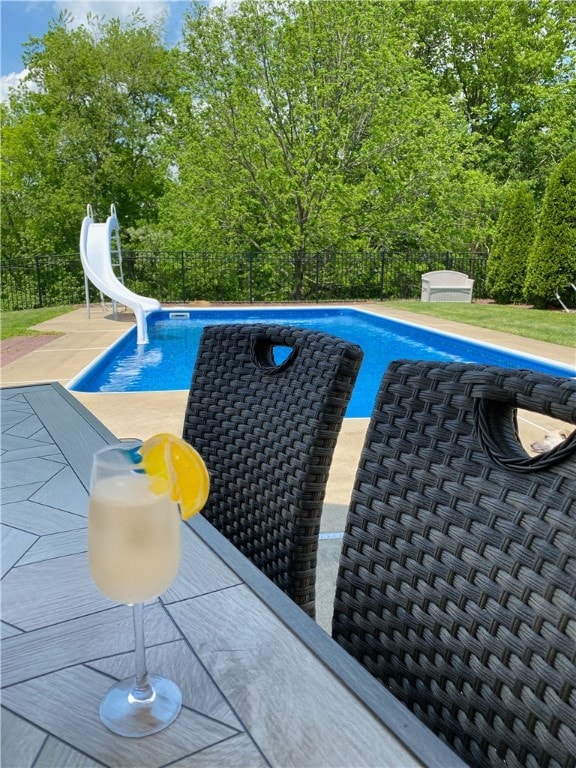 view of swimming pool with a water slide and a patio area