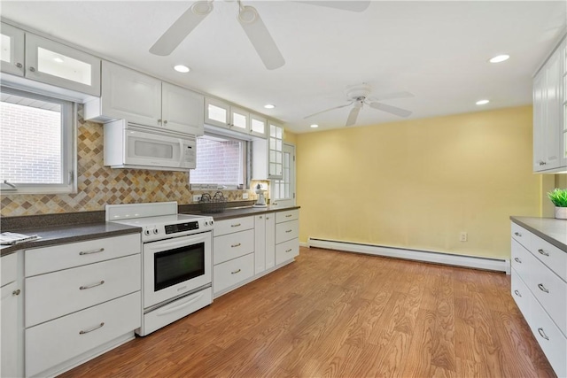 kitchen with white appliances, baseboard heating, backsplash, light hardwood / wood-style floors, and white cabinets