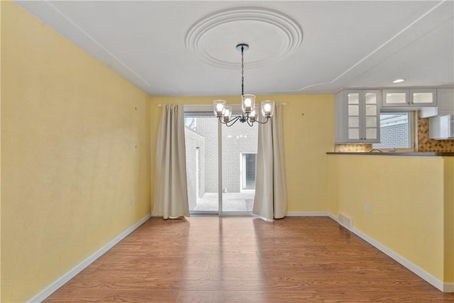 unfurnished dining area featuring an inviting chandelier and wood-type flooring