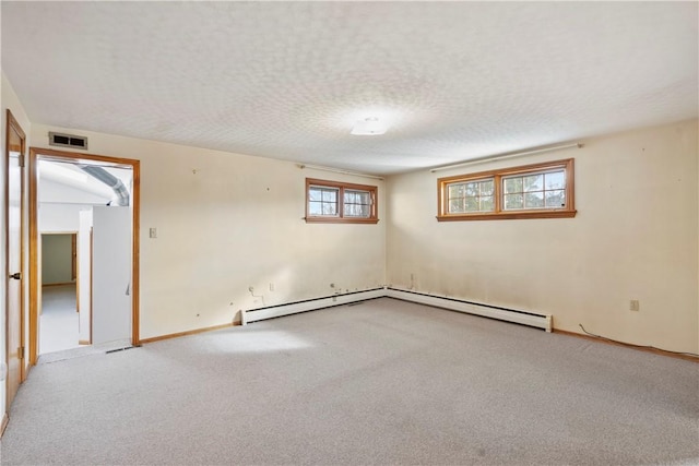 spare room featuring a baseboard radiator, carpet flooring, and a textured ceiling