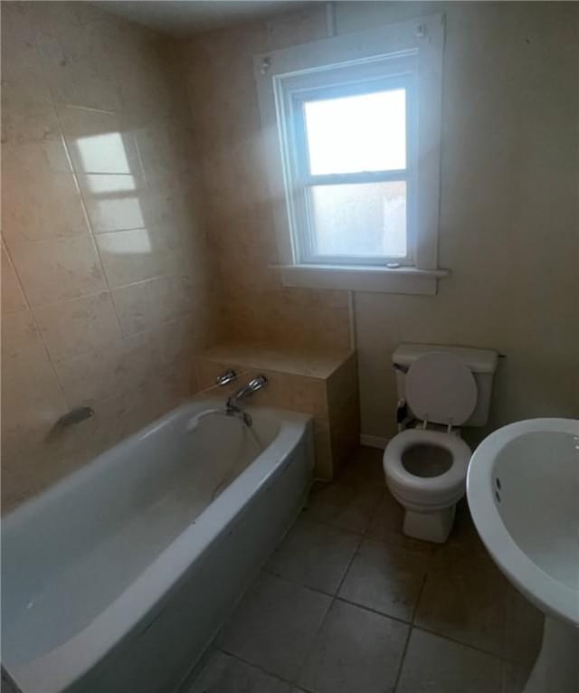 bathroom with tile patterned flooring, sink, a tub, and toilet