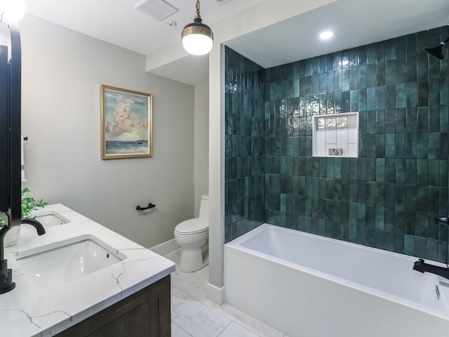 full bathroom featuring tiled shower / bath, vanity, and toilet