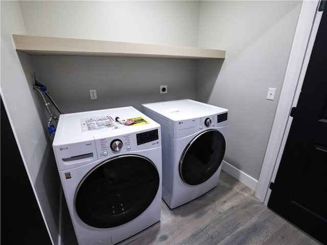 clothes washing area with hardwood / wood-style floors and washer and clothes dryer