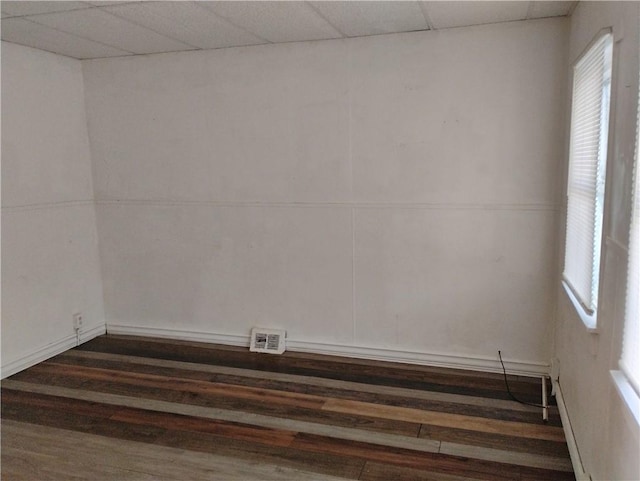 unfurnished room with dark wood-type flooring and a drop ceiling