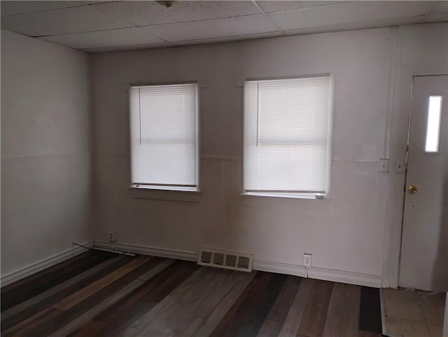 unfurnished room featuring a drop ceiling, a wealth of natural light, and dark wood-type flooring