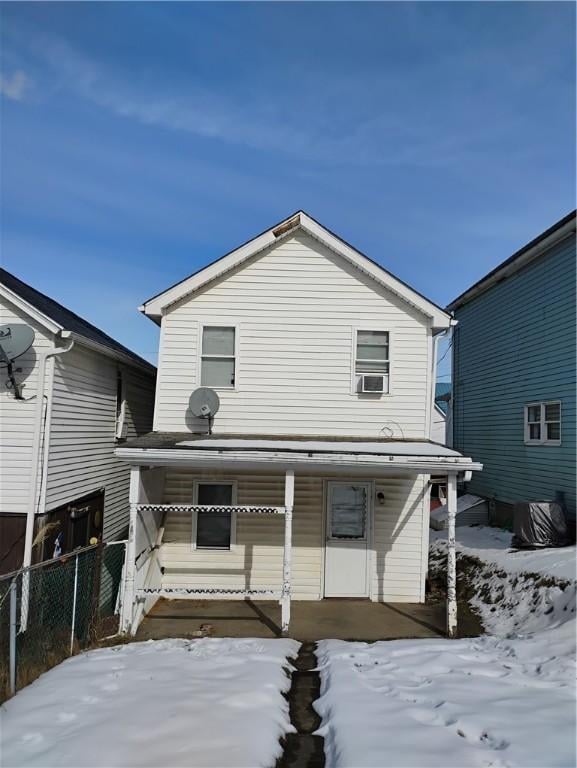 snow covered rear of property with cooling unit and covered porch