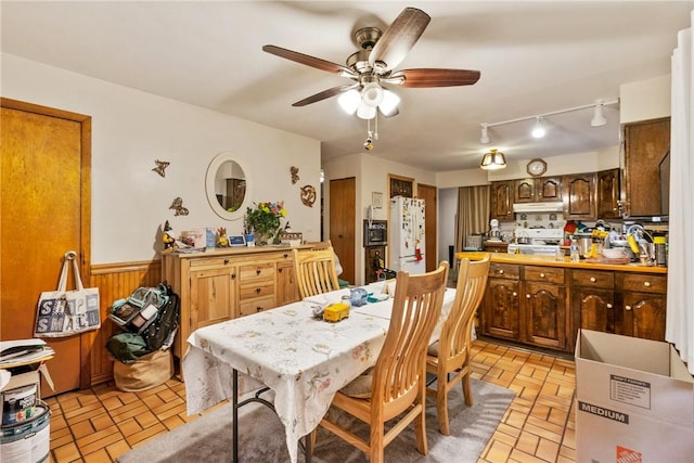 dining area with ceiling fan and wood walls