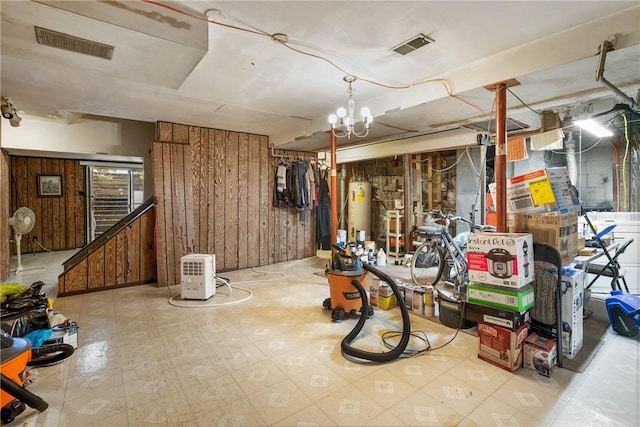 basement featuring gas water heater, a chandelier, and wooden walls