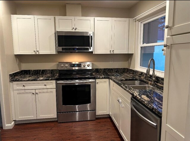 kitchen with sink, dark stone counters, white cabinets, and appliances with stainless steel finishes