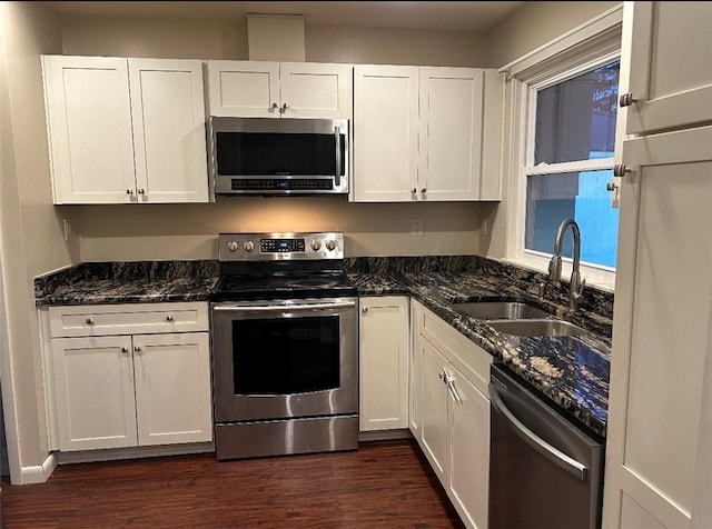 kitchen featuring stainless steel appliances, sink, dark stone counters, and white cabinets