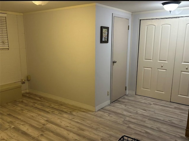 hallway with ornamental molding and light hardwood / wood-style floors