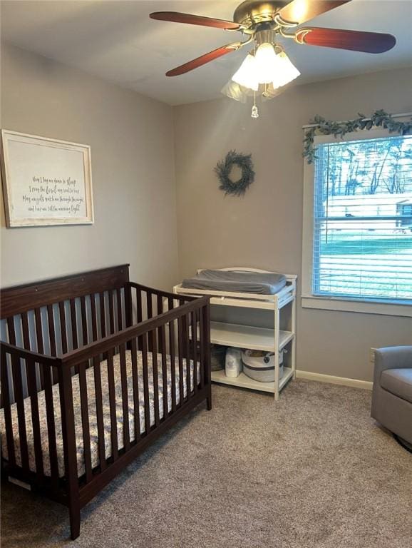 carpeted bedroom featuring a crib and ceiling fan