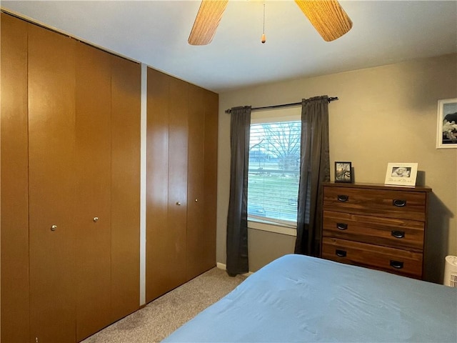 carpeted bedroom with multiple closets and ceiling fan