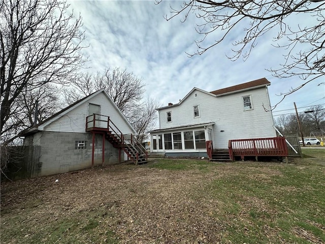 rear view of house featuring a sunroom, a yard, and a deck