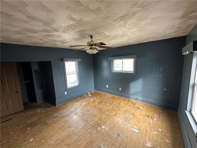 unfurnished bedroom with multiple windows, wood-type flooring, and a textured ceiling