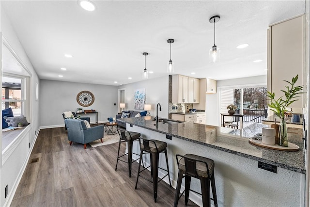 kitchen with hardwood / wood-style flooring, sink, a kitchen breakfast bar, and decorative light fixtures