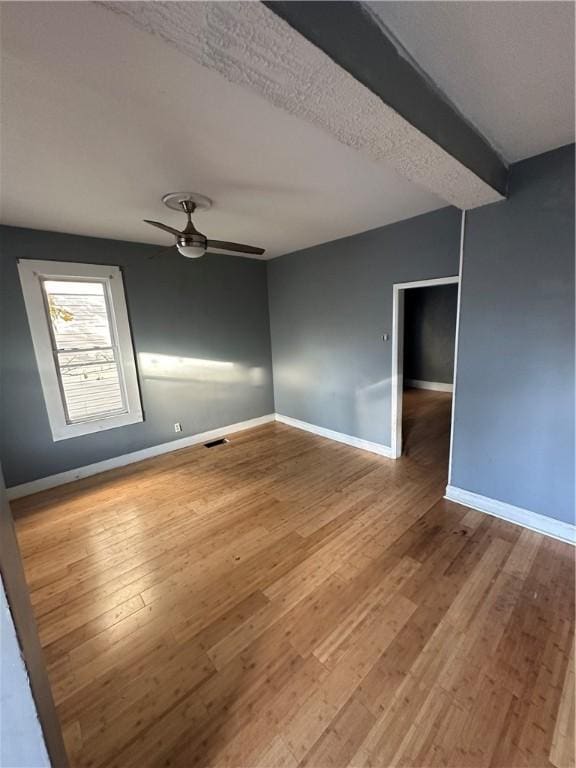 unfurnished room with hardwood / wood-style flooring, ceiling fan, and beam ceiling