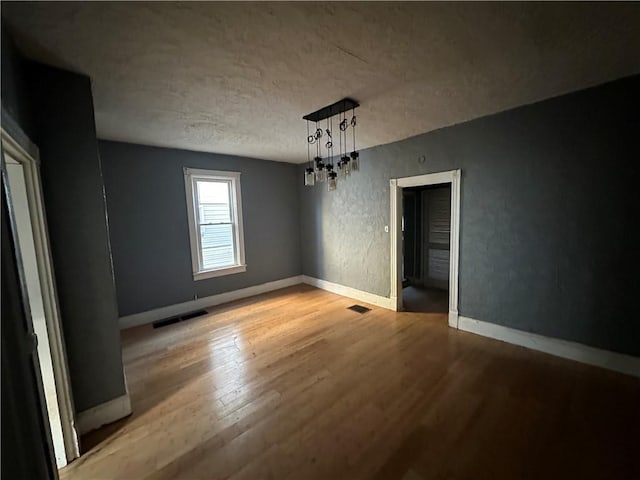 unfurnished dining area with a textured ceiling and light wood-type flooring