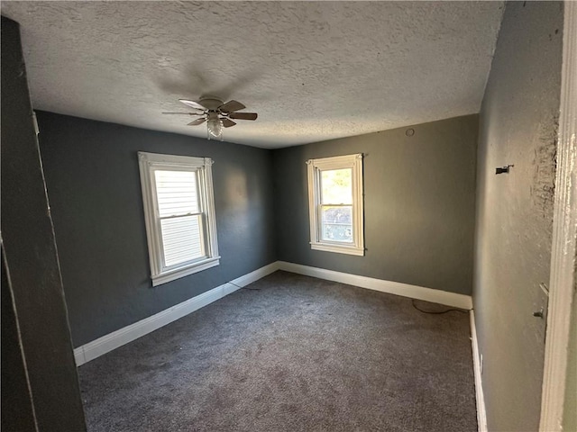 empty room featuring dark colored carpet, ceiling fan, and a textured ceiling