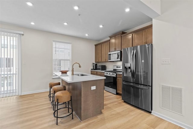 kitchen featuring an island with sink, sink, a kitchen bar, stainless steel appliances, and a healthy amount of sunlight