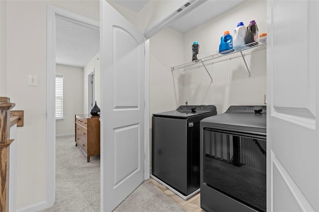 laundry area with washer and clothes dryer and light colored carpet