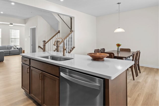 kitchen with pendant lighting, dishwasher, sink, dark brown cabinets, and a center island with sink