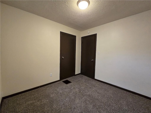 empty room with carpet and a textured ceiling