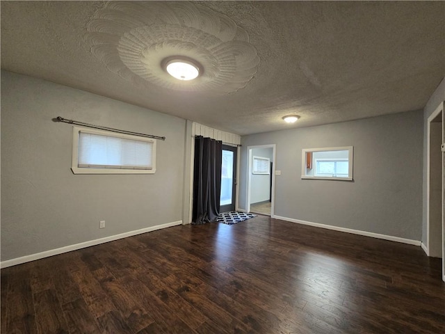 empty room with dark wood-type flooring and a textured ceiling