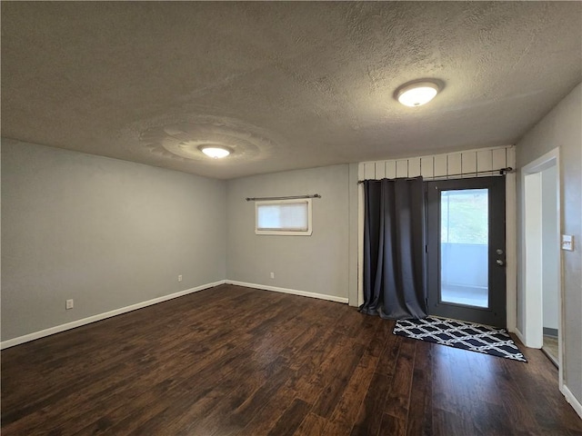 unfurnished room featuring dark wood-type flooring and a textured ceiling