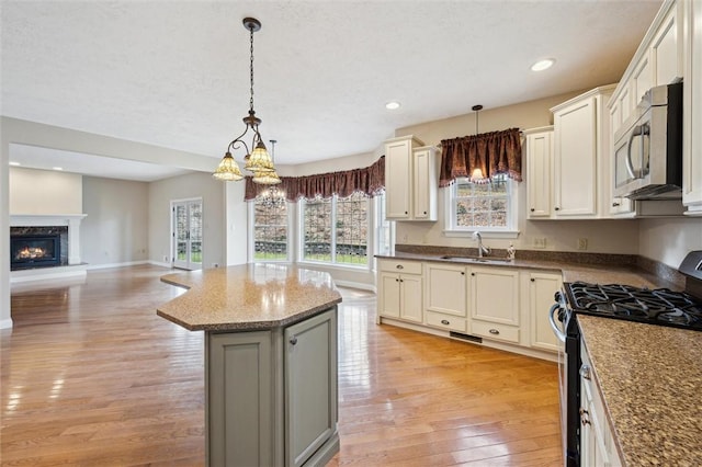 kitchen featuring hanging light fixtures, range with gas cooktop, light hardwood / wood-style floors, and a kitchen island