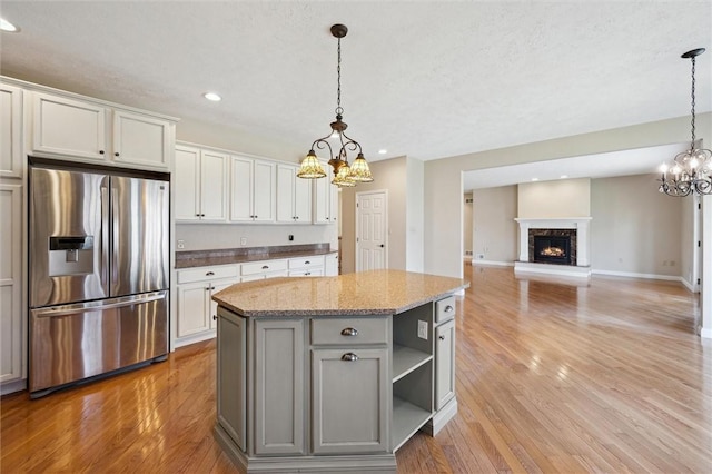 kitchen featuring stainless steel refrigerator with ice dispenser, pendant lighting, a center island, and white cabinets