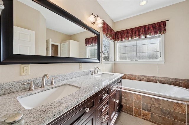 bathroom featuring tile patterned flooring, tiled tub, and vanity