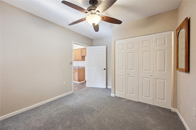 unfurnished bedroom featuring ceiling fan, dark carpet, and a closet