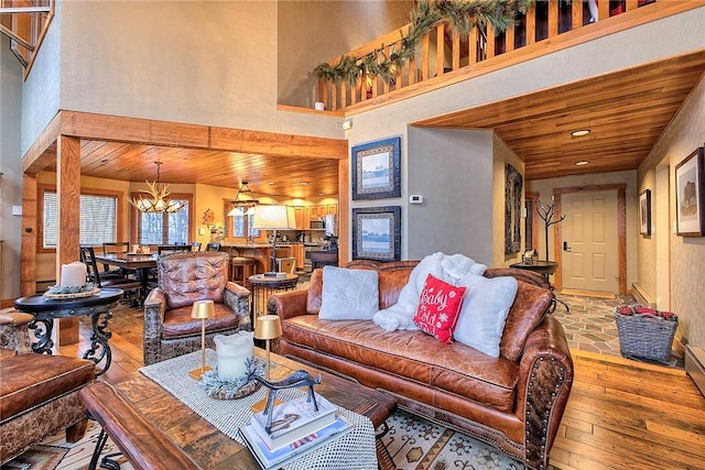 living room featuring a notable chandelier, a towering ceiling, wooden ceiling, and light hardwood / wood-style floors