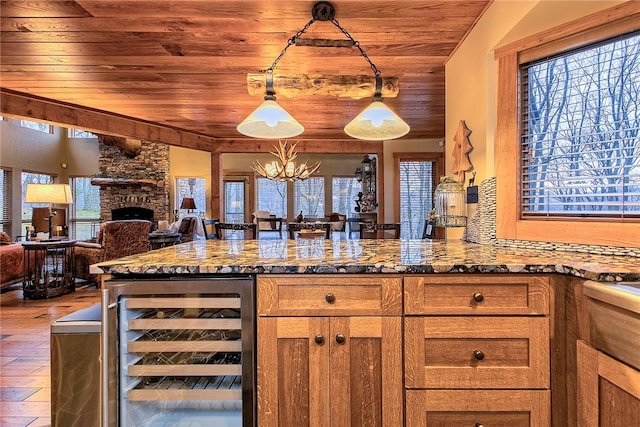 kitchen featuring lofted ceiling, wooden ceiling, beverage cooler, pendant lighting, and a fireplace