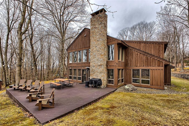 rear view of house featuring a wooden deck and a lawn