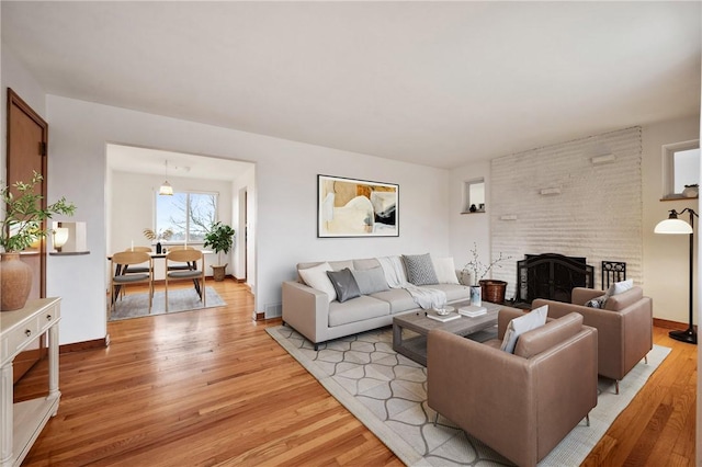 living room featuring a brick fireplace and light hardwood / wood-style flooring