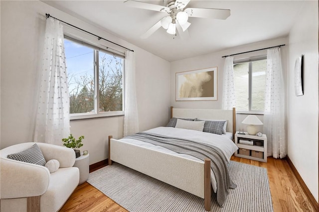 bedroom with multiple windows, ceiling fan, and light hardwood / wood-style flooring