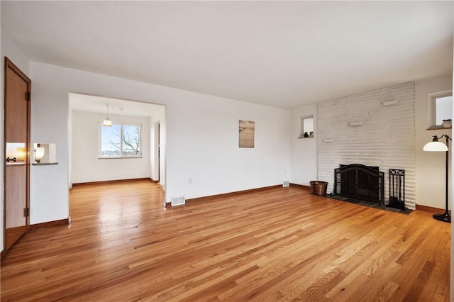 unfurnished living room featuring a fireplace and light hardwood / wood-style floors